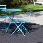A light blue bistro table and chairs set on a round grey outdoor rug (1)