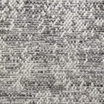 A macro shot of a textured weave showing a tight interlacing of neutral-toned yarns, creating a subtle zigzag or diamond motif.