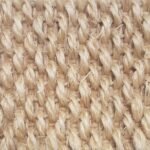 Close-up of a light cream or sandy-colored natural fiber rug with a thick, rope-like weave.