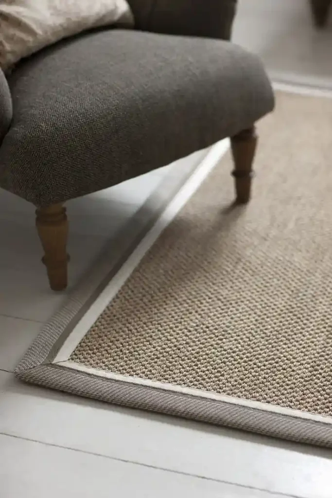 Natural woven rug with bound edge near upholstered furniture