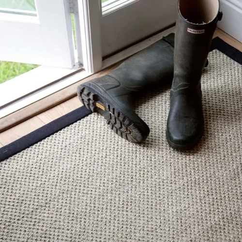 rug-with-a-black-border-placed-by-a-door-with-rubber-boots-on-top