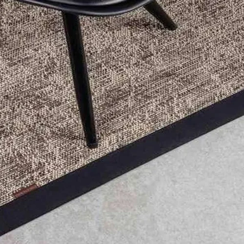 textured-brown-and-beige-woven-rug-with-a-thick-black-border-featuring-a-black-chair-leg-resting-on-it